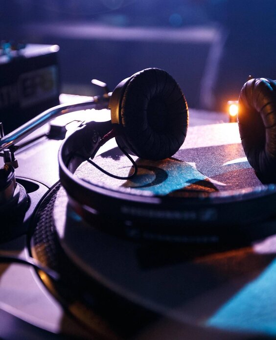 Un giradischi con cuffie sovraurali posizionate sopra. L'atmosfera è luminosa e intensa, tipica di un ambiente musicale.