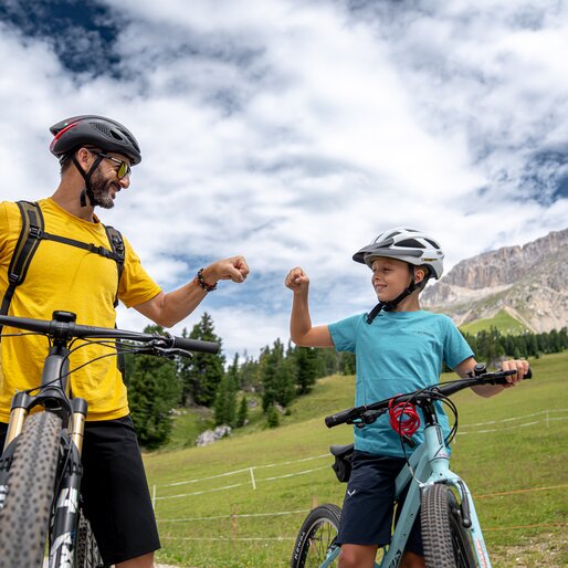 Padre e figlio in sella alla loro bici si danno il pugno | © APT Fiemme e Cembra - Mattia Rizzi
