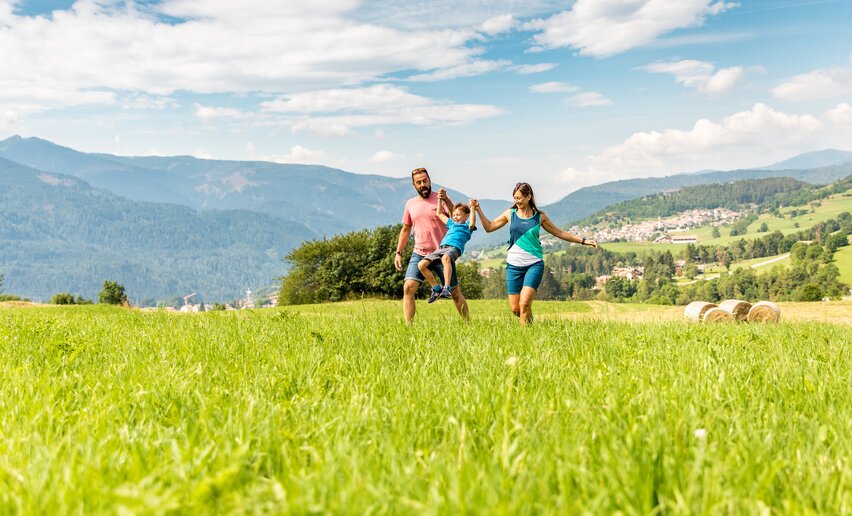 Genitori con bambino passeggiano nei prati di Varena | © APT Fiemme e Cembra - Gaia Panozzo