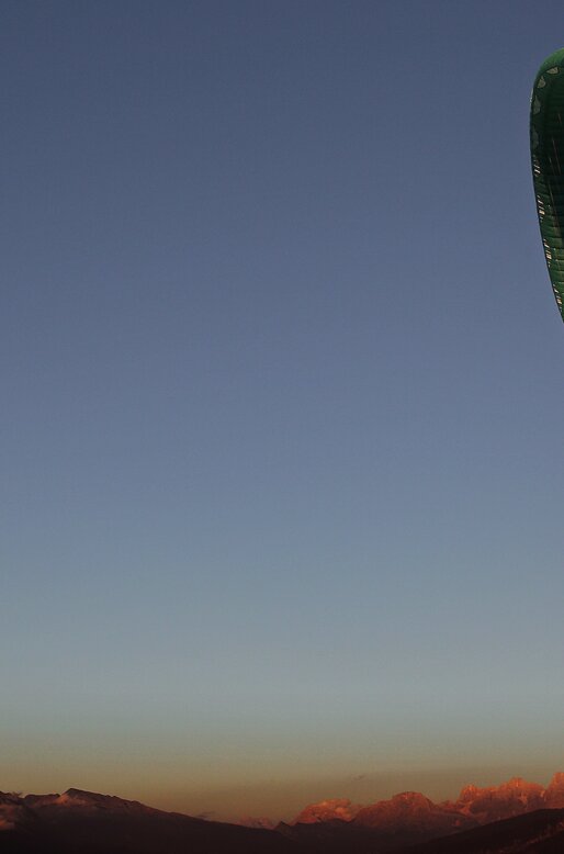 Parapendista all'imbrunire con Pale di San Martino sullo sfondo | © APT Fiemme e Cembra