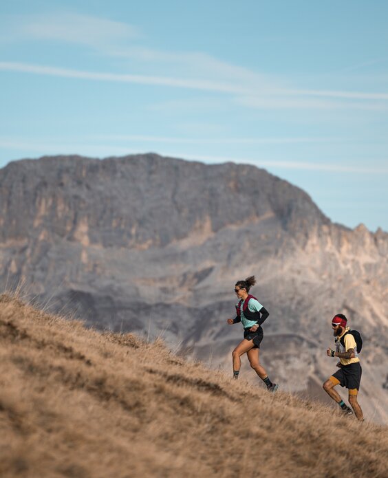 Due trail runners corrono con il Latemar sullo sfondo | © APT Fiemme e Cembra - foto di Gaia Panozzo