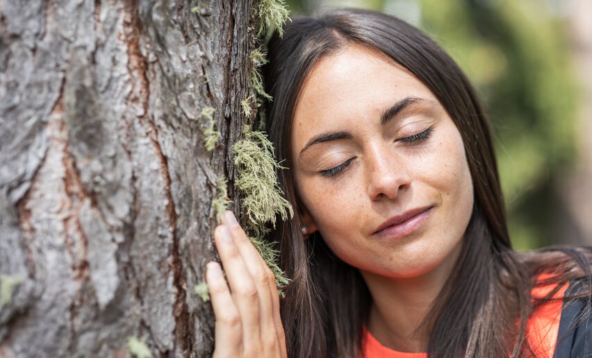 Ragazza ad occhi chiusi poggia la testa su un albero | © APT Fiemme e Cembra - Gaia Panozzo