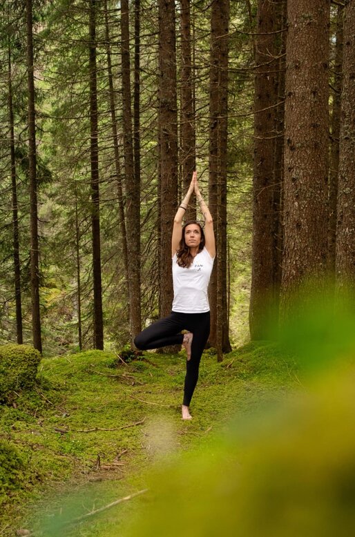 Ragazza fa la posizione dell'albero nel bosco | © APT Fiemme e Cembra