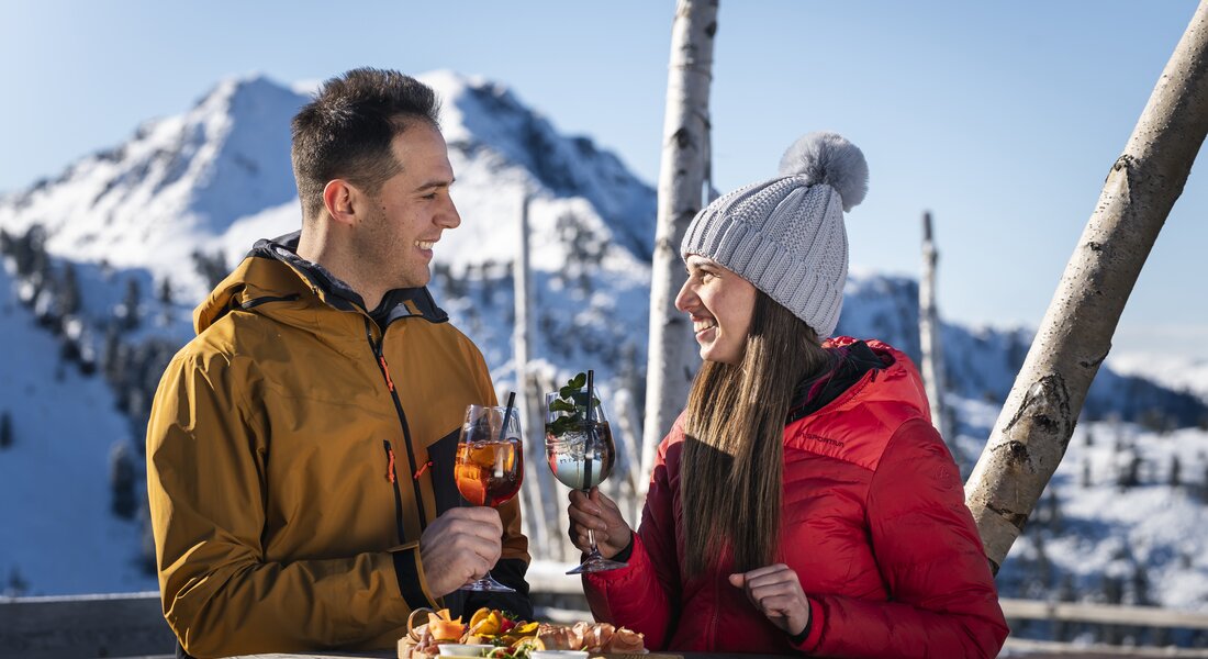 Coppia si gode un aperitivo sulla terrazza del Rifugio Pajon all'Alpe Cermis | © APT Fiemme e Cembra