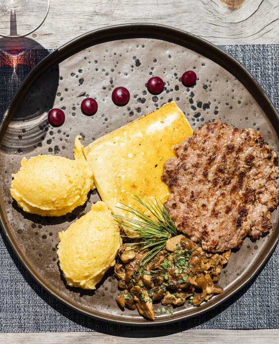 Polenta con funghi, formaggio e lucanica accompagnata da un bicchiere di vino rosso  | © APT Fiemme e Cembra - Gaia Panozzo